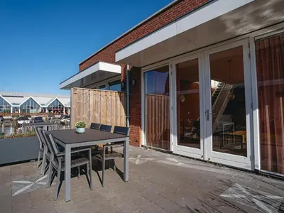 a patio with a table and chairs on a balcony at Modern Waterfront Retreat in Uitgeest