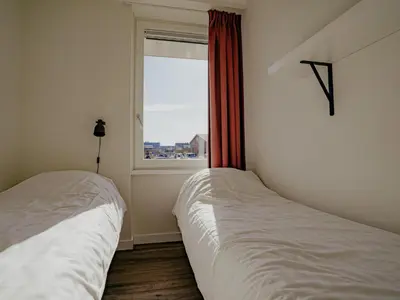 two beds in a bedroom with a window at Modern Waterfront Retreat in Uitgeest
