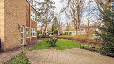 a bench sitting in the grass next to a brick building at Huize Bech in Bergen