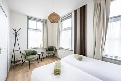 two beds in a room with windows at Hotel Over de Brug in Haastrecht