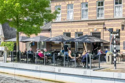 a group of people sitting at tables under umbrellas at Hotel Over de Brug in Haastrecht