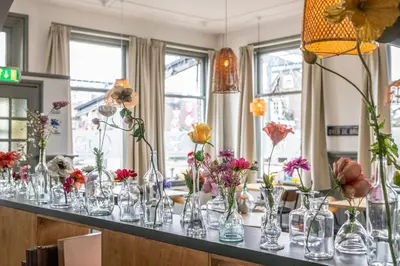 a table with many glass vases filled with flowers at Hotel Over de Brug in Haastrecht
