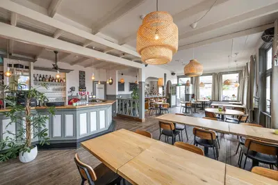 a restaurant with tables and chairs and a bar at Hotel Over de Brug in Haastrecht