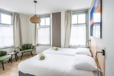 two beds in a hotel room with windows at Hotel Over de Brug in Haastrecht