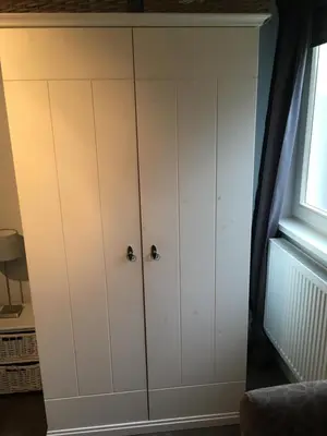 a wardrobe with white cabinets in a room with a window at Halte71 in Zandvoort