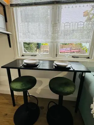 a table and two stools in front of a window at Hello Noordwijk - Tiny House Dahliastraat 60 in Noordwijk aan Zee