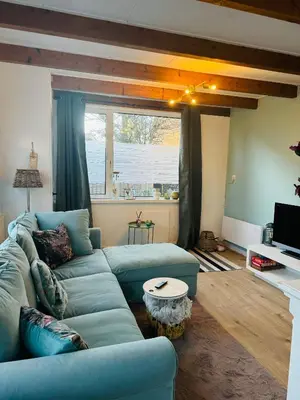 a living room with a blue couch and a table at Hello Noordwijk - Tiny House Dahliastraat 60 in Noordwijk aan Zee