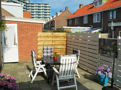a patio with a table and chairs and a fence at Vakantiehuis Voor Anker in Egmond aan Zee