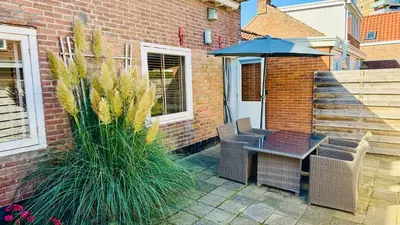 a patio with a table and chairs and an umbrella at Vakantiehuis Voor Anker in Egmond aan Zee