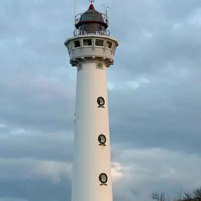 a white lighthouse with a red roof on top at Sterflat 101 in Egmond aan Zee