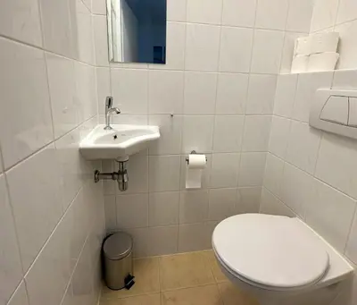 a white bathroom with a toilet and a sink at Sterflat 101 in Egmond aan Zee