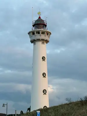 a lighthouse on top of a grassy hill at Sterflat 101 in Egmond aan Zee