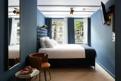 a bedroom with a bed with blue walls and a window at Stanley Collection Hotel Hegra Amsterdam in Amsterdam