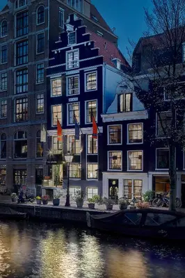 a building with flags in front of a river at Stanley Collection Hotel Hegra Amsterdam in Amsterdam