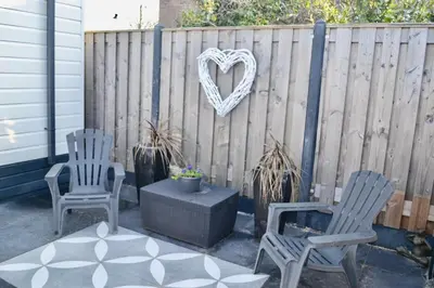 two chairs and a heart sign on a fence at Chalet 27 in Zandvoort