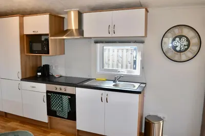 a kitchen with a sink and a clock on the wall at Chalet 27 in Zandvoort