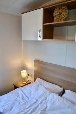 a bedroom with a white bed and a lamp at Chalet 27 in Zandvoort