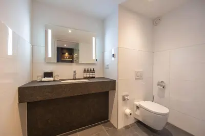 a bathroom with a sink and a toilet and a mirror at Grand Hotel Amrâth Amsterdam in Amsterdam
