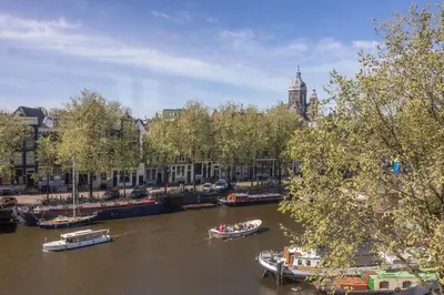 a river with boats in a city with buildings at Grand Hotel Amrâth Amsterdam in Amsterdam