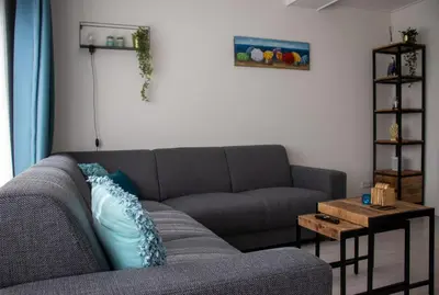 a living room with a gray couch and a table at Zeezand in Egmond aan Zee