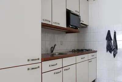 a kitchen with white cabinets and a sink at Zeezand in Egmond aan Zee