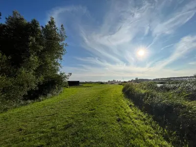 a field of grass with the sun in the sky at De Fuut in Nieuwe-Niedorp