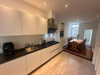 a kitchen with white cabinets and a table in a room at Tulip House Luxury Apartment - Top Location - Rijksmuseum - Leidseplein AMSTERDAM Central 120 m2 ALL Private with kitchen in Amsterdam