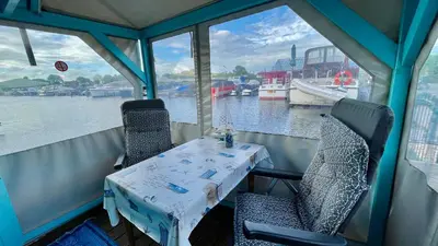 a table and chairs on a boat in the water at Island Sleeping in Aalsmeer