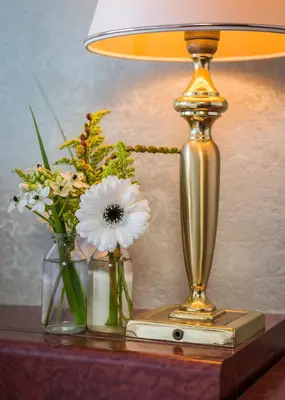 a lamp on a table with flowers in vases at Prominent Inn Hotel in Noordwijk aan Zee