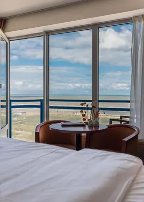 a bedroom with a bed and a view of the ocean at Prominent Inn Hotel in Noordwijk aan Zee