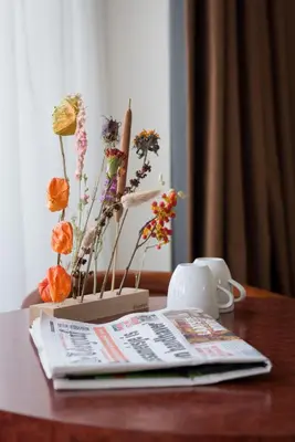 a table with a magazine and flowers on it at Prominent Inn Hotel in Noordwijk aan Zee