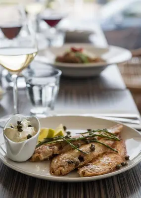 a plate of food with fish and vegetables on a table at Prominent Inn Hotel in Noordwijk aan Zee