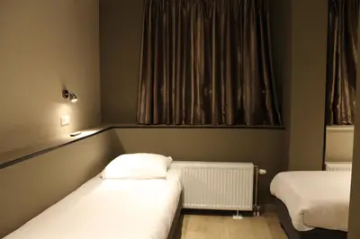 a small room with two beds and a window at Blossoms City Hotel in Amsterdam