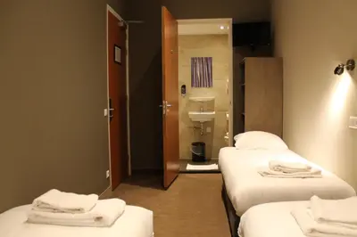 a room with three beds and a bathroom with a sink at Blossoms City Hotel in Amsterdam