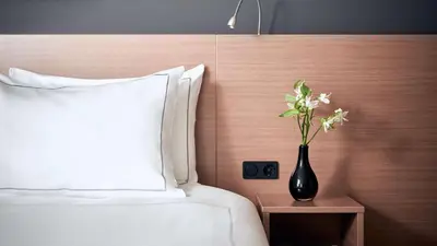 a black vase with flowers on a night stand next to a bed at Park Plaza Amsterdam Airport in Lijnden