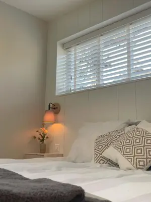 a white bedroom with a bed and a window at Villa de Duinfazant in Bergen aan Zee
