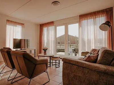 a living room with a couch and a television at Apartment Westergeest-1 by Interhome in Uitgeest