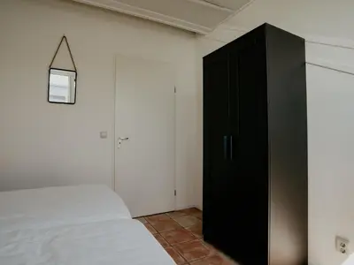 a bedroom with a bed and a black cabinet at Apartment Oostergeest by Interhome in Uitgeest