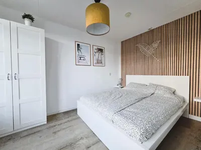a white bedroom with a bed and a pendant light at Moana 1 in Egmond aan Zee