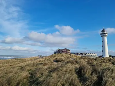 a lighthouse sitting on top of a hill next to the ocean at Moana 1 in Egmond aan Zee