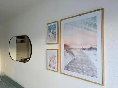 three framed pictures on a wall with a mirror at Moana 1 in Egmond aan Zee