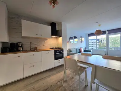 a kitchen with white cabinets and a table with chairs at Moana 1 in Egmond aan Zee