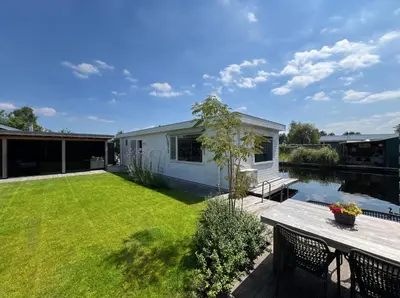 a garden with a deck and a house at New- Private Cosy Houseboat, on a lake near Amsterdam in Vinkeveen