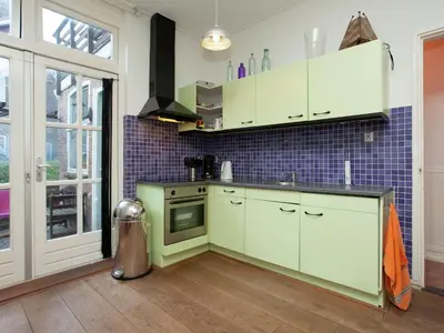 a kitchen with white cabinets and blue tiles at Holiday Home in Alkmaar by Canal in Alkmaar