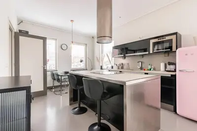 a kitchen with a sink and a counter with chairs at Hello Noordwijk - Wellness Huis Schoolstraat 47B in Noordwijk aan Zee