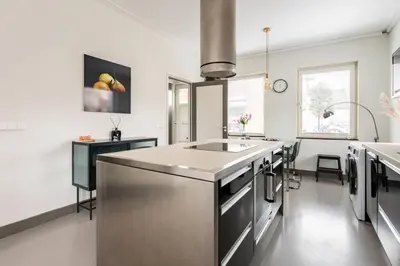 a kitchen with white walls and a stainless steel island at Hello Noordwijk - Wellness Huis Schoolstraat 47B in Noordwijk aan Zee