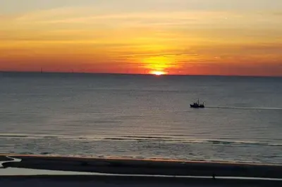 a boat in the ocean with the sunset in the background at Solaris in Egmond aan den Hoef