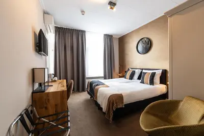 a hotel room with a bed and a chair at Hotel Montfoort in Montfoort