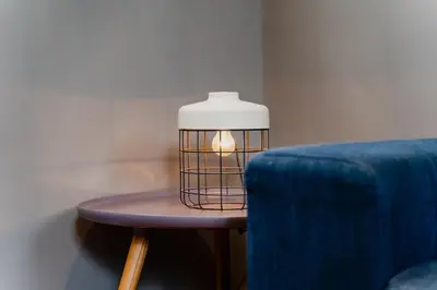 a lamp on a table next to a blue chair at Apartments De Hallen in Amsterdam