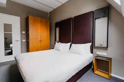a bedroom with a large white bed with a wooden headboard at Apartments De Hallen in Amsterdam